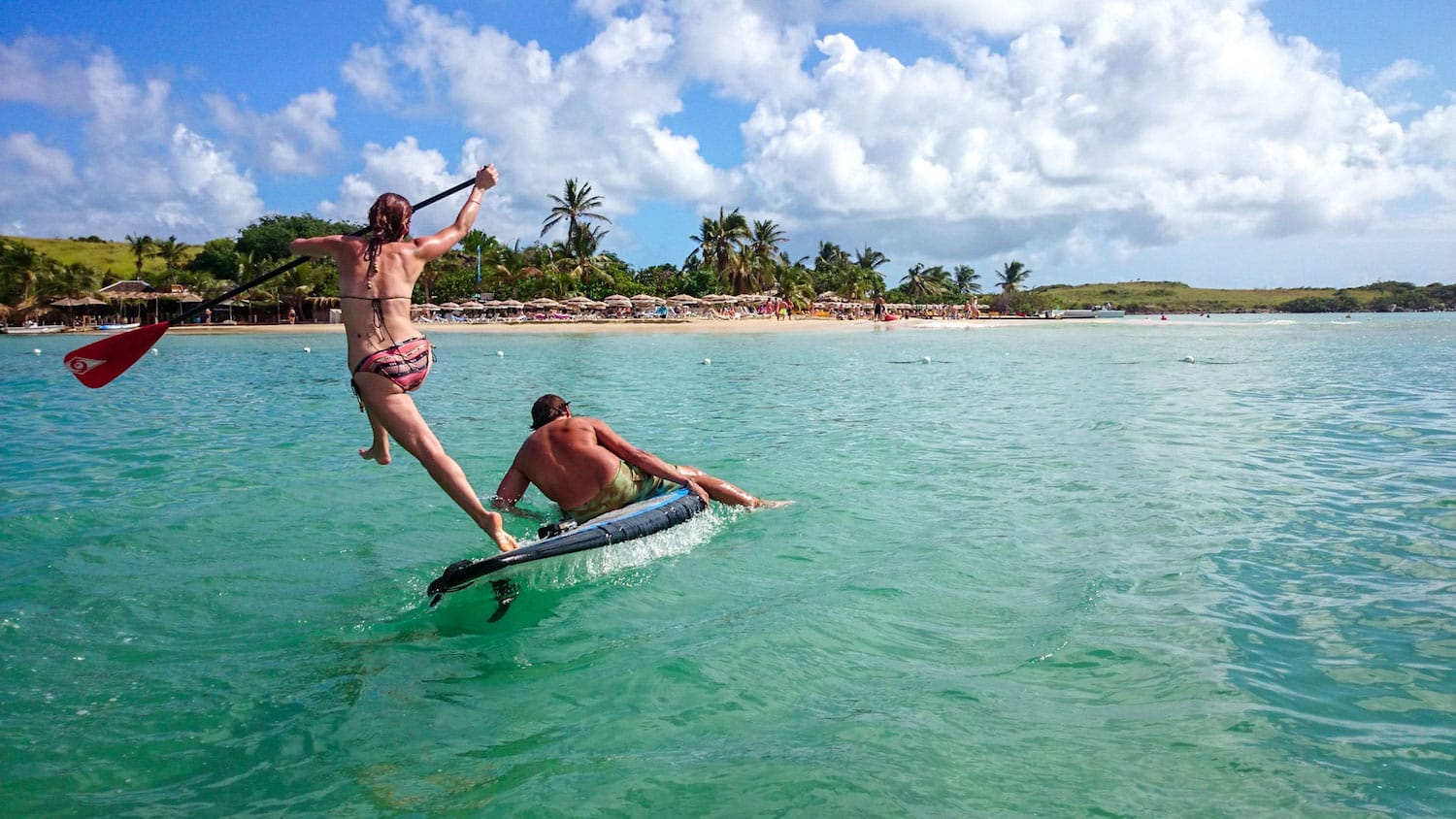 A man and a woman are riding a paddle board in the ocean.