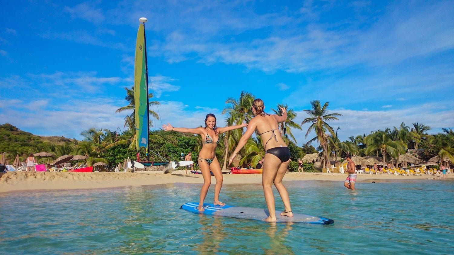2 girls having fun on a paddle board in front of Pinel island