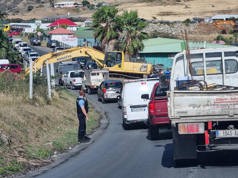Cars struggle to pass a bulldozer near Orient Bay