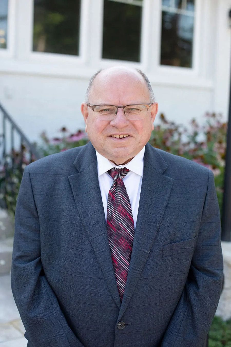 One of the owners of Armes-Funeral Home and Cremation Services in Indiana. They are wearing a gray suit, white shirt and red striped tie