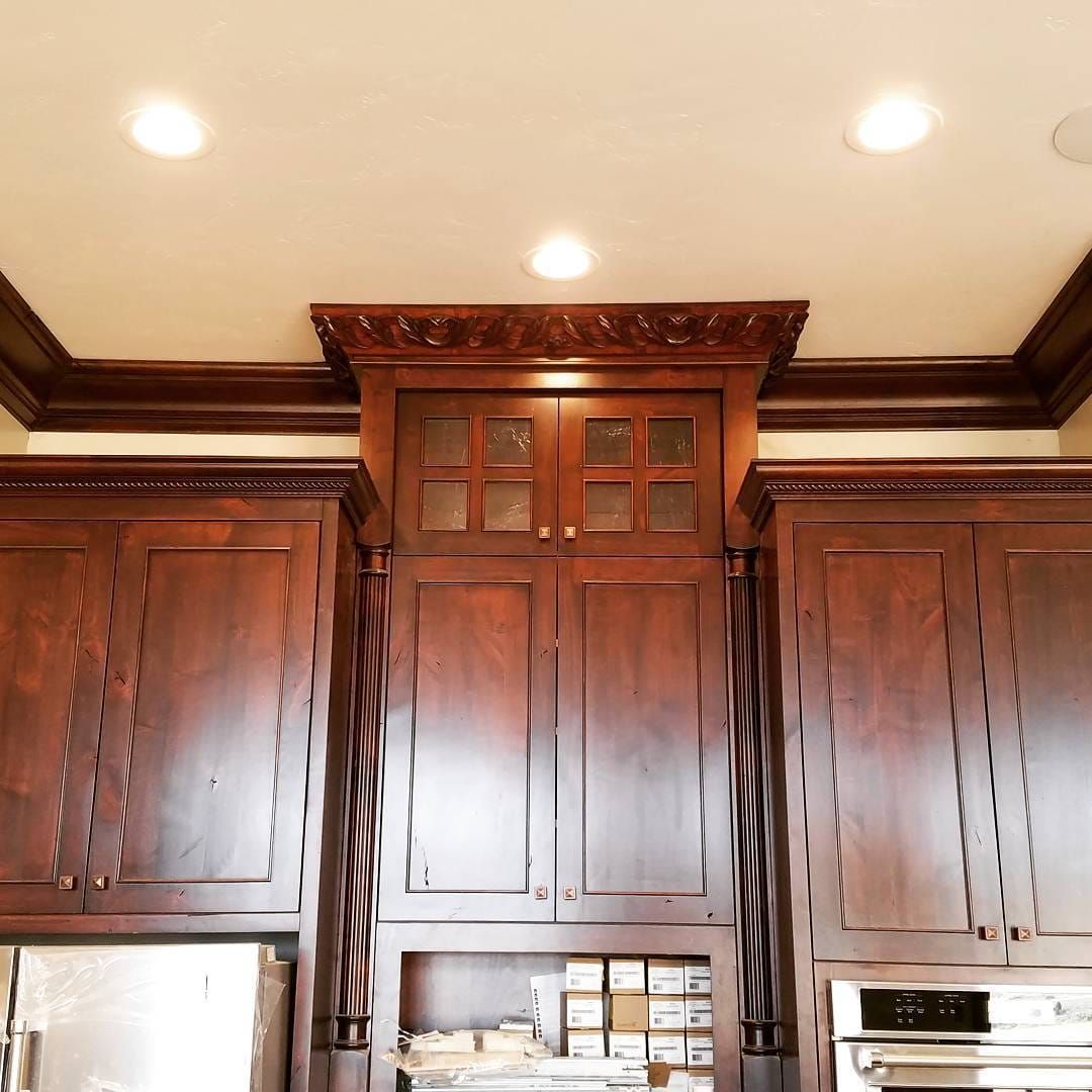 Dark wood kitchen cabinets with decorative crown molding and ceiling lights.