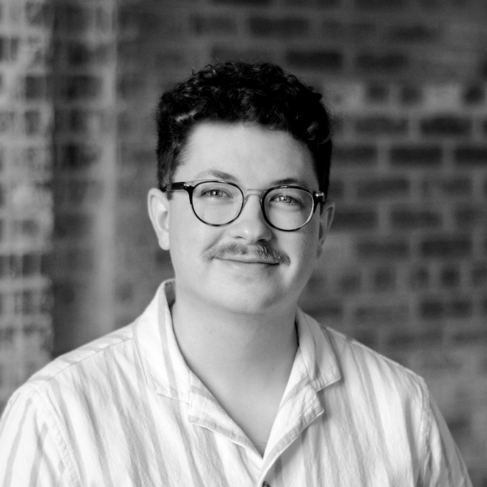 A black and white photo of a man wearing glasses and a mustache.