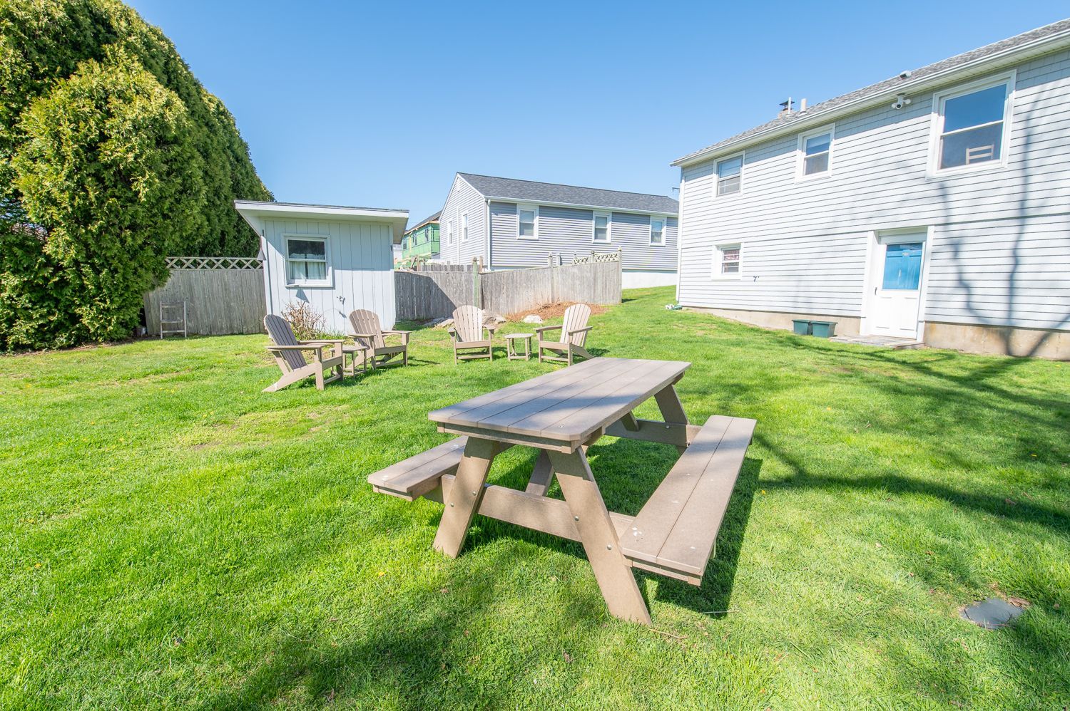 A picnic table and chairs are in the backyard of a house.