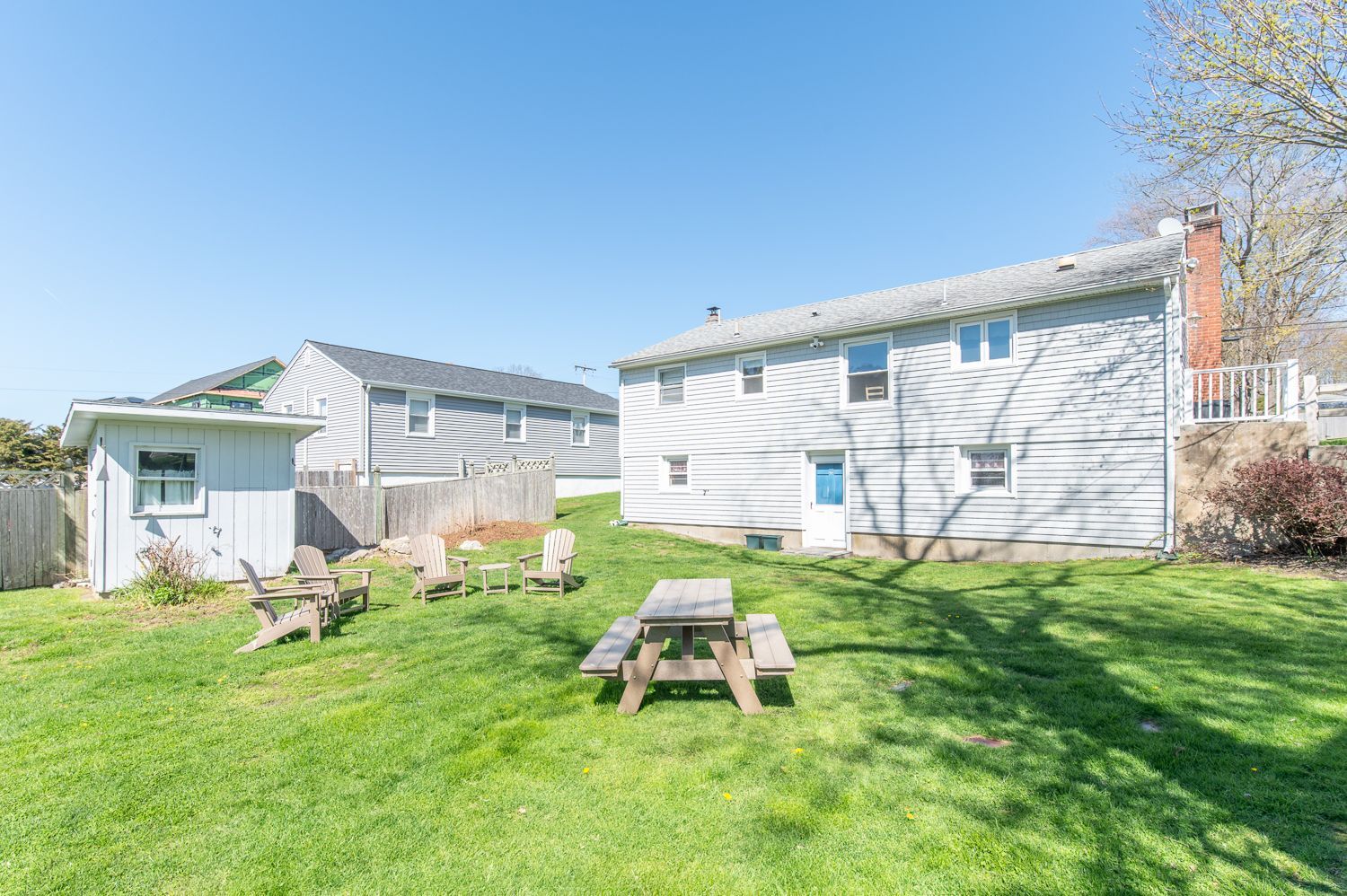 A backyard with a picnic table and chairs in front of a house.