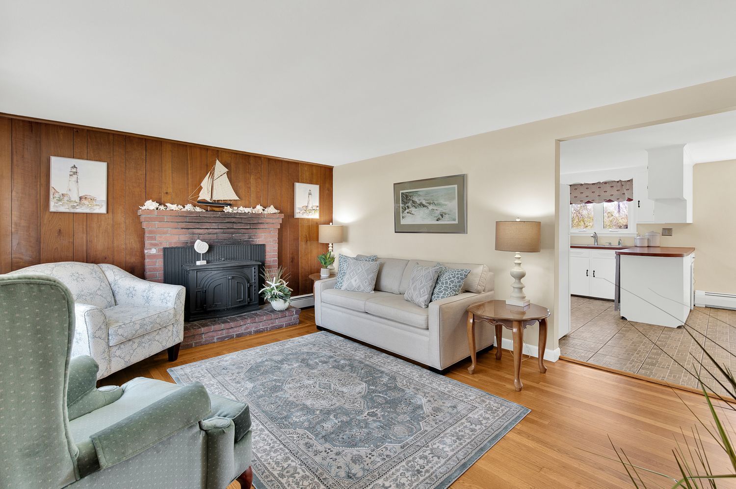 A living room with a couch , chair , rug and fireplace.