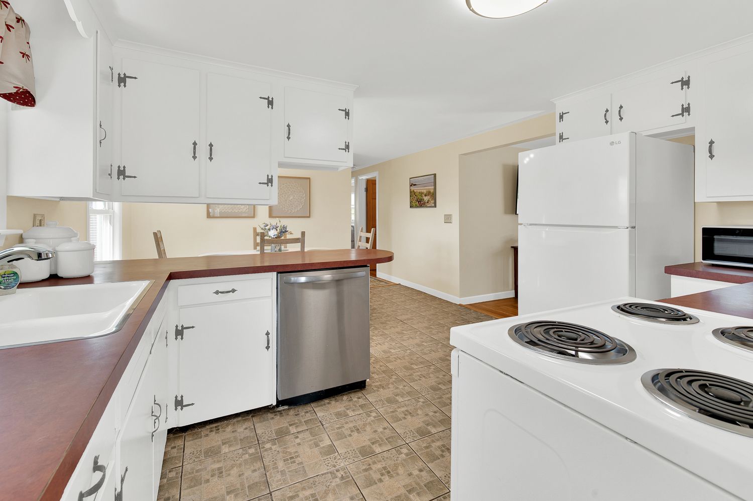 A kitchen with white cabinets and a white stove top oven