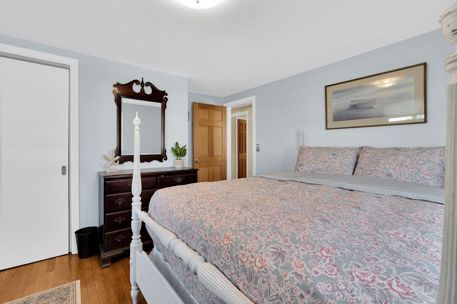 A bedroom with a king size bed , dresser and mirror.