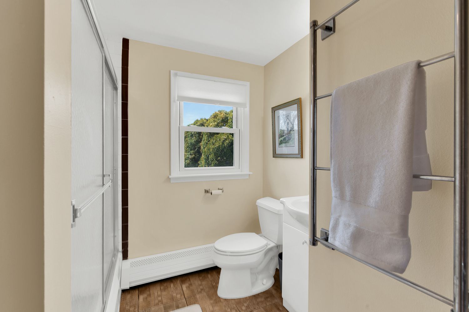 A bathroom with a toilet , sink , and window.
