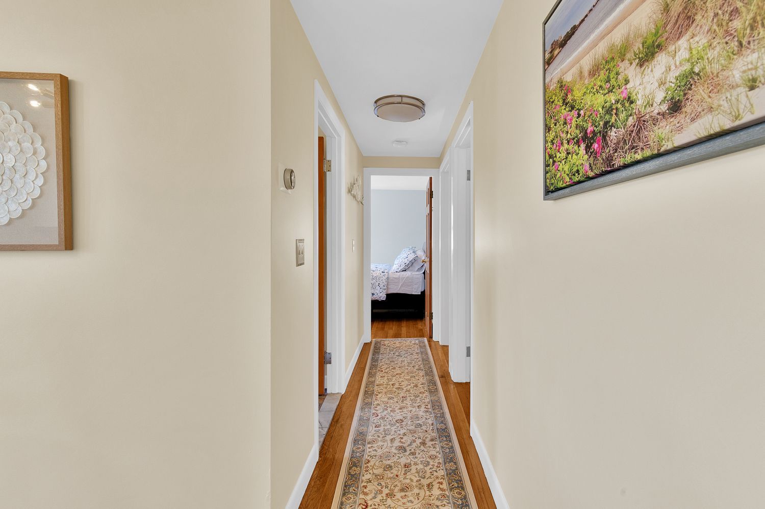 A long hallway with a rug on the floor and a picture on the wall.