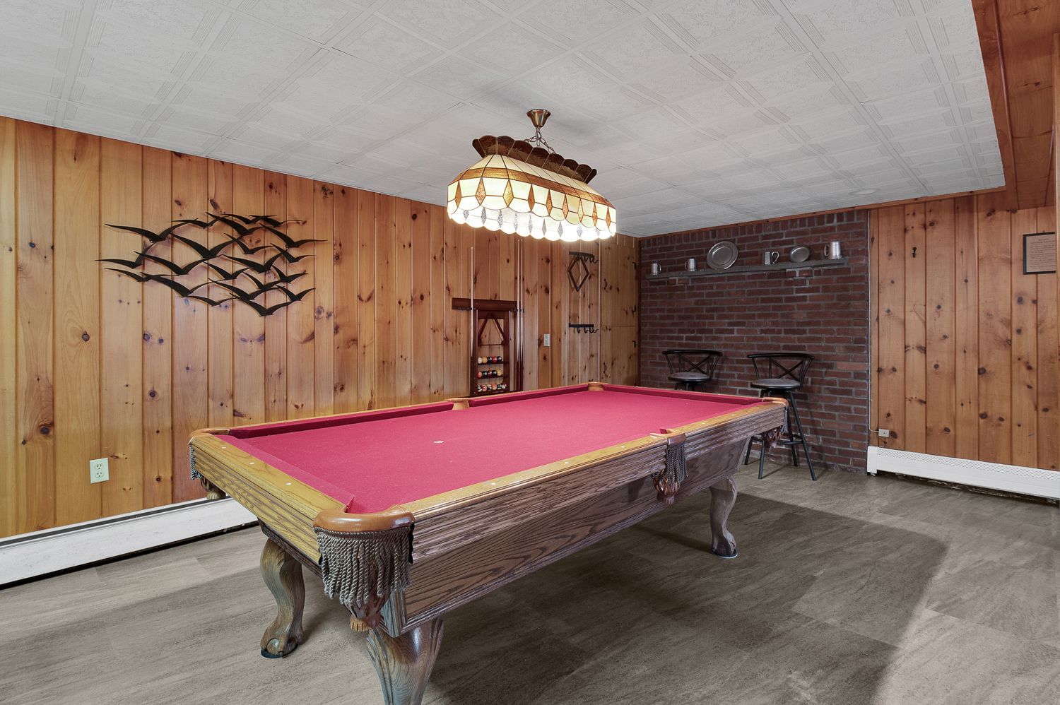 A pool table in a room with wood paneling and a chandelier.