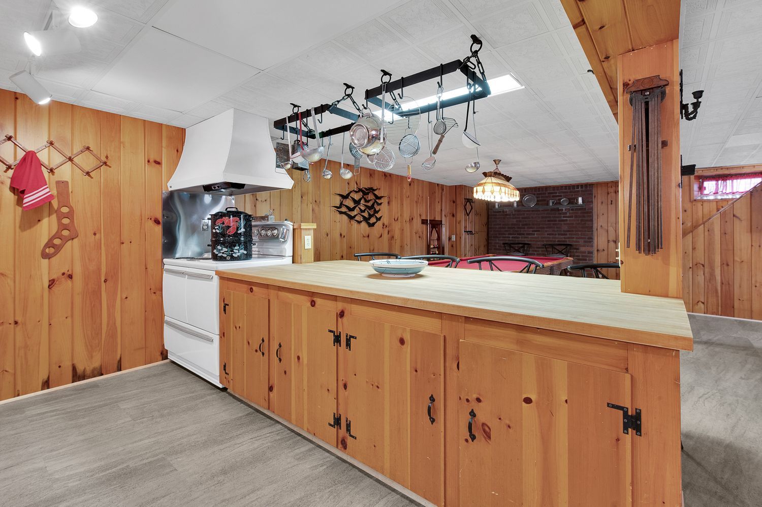 A kitchen with wooden cabinets , a stove , and a pool table.