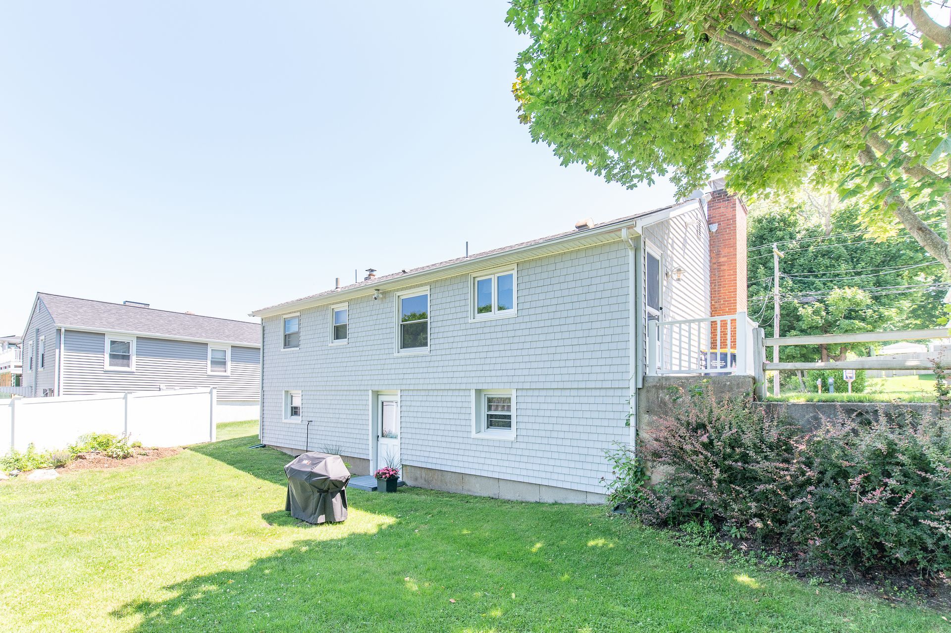 A large white house with a lot of windows is sitting on top of a lush green lawn.