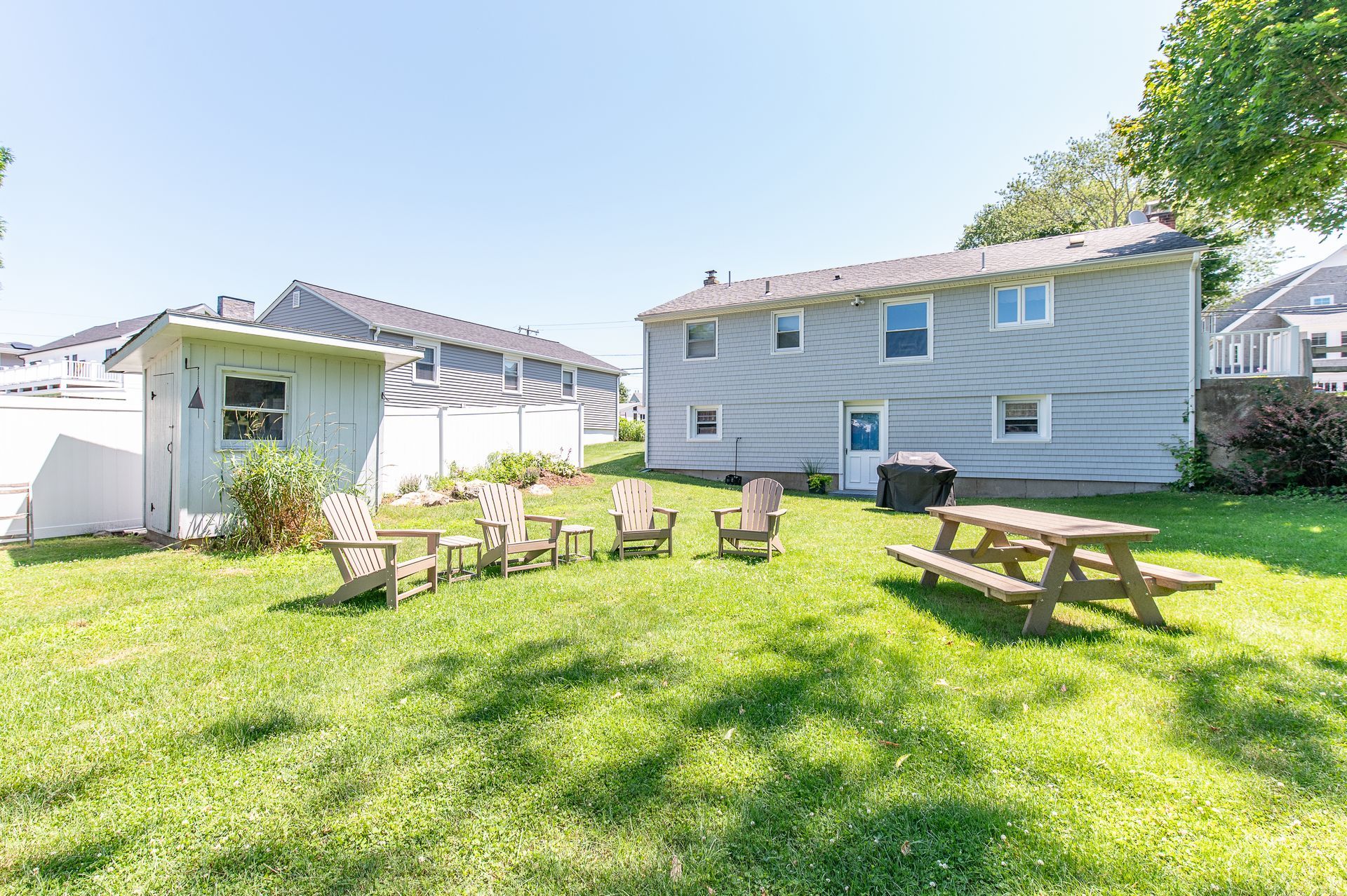 A backyard with a picnic table and chairs in front of a house.