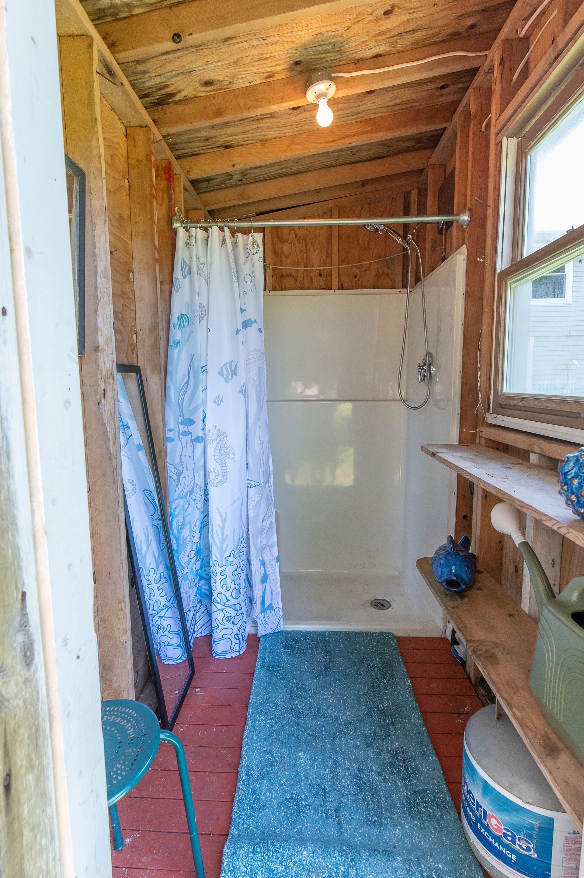 A small bathroom with a shower and a window.