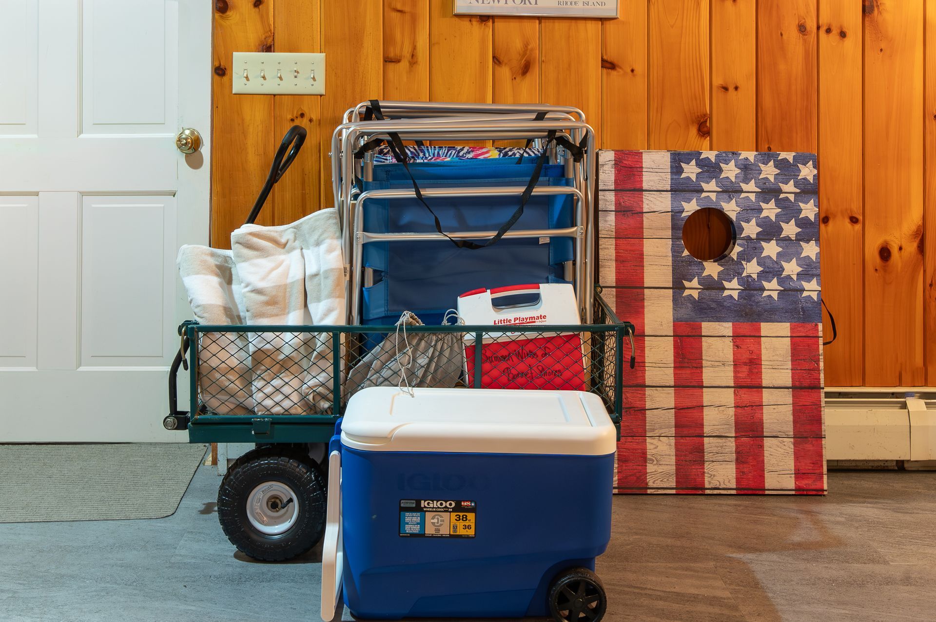 A blue cooler is sitting on the floor next to a wagon.