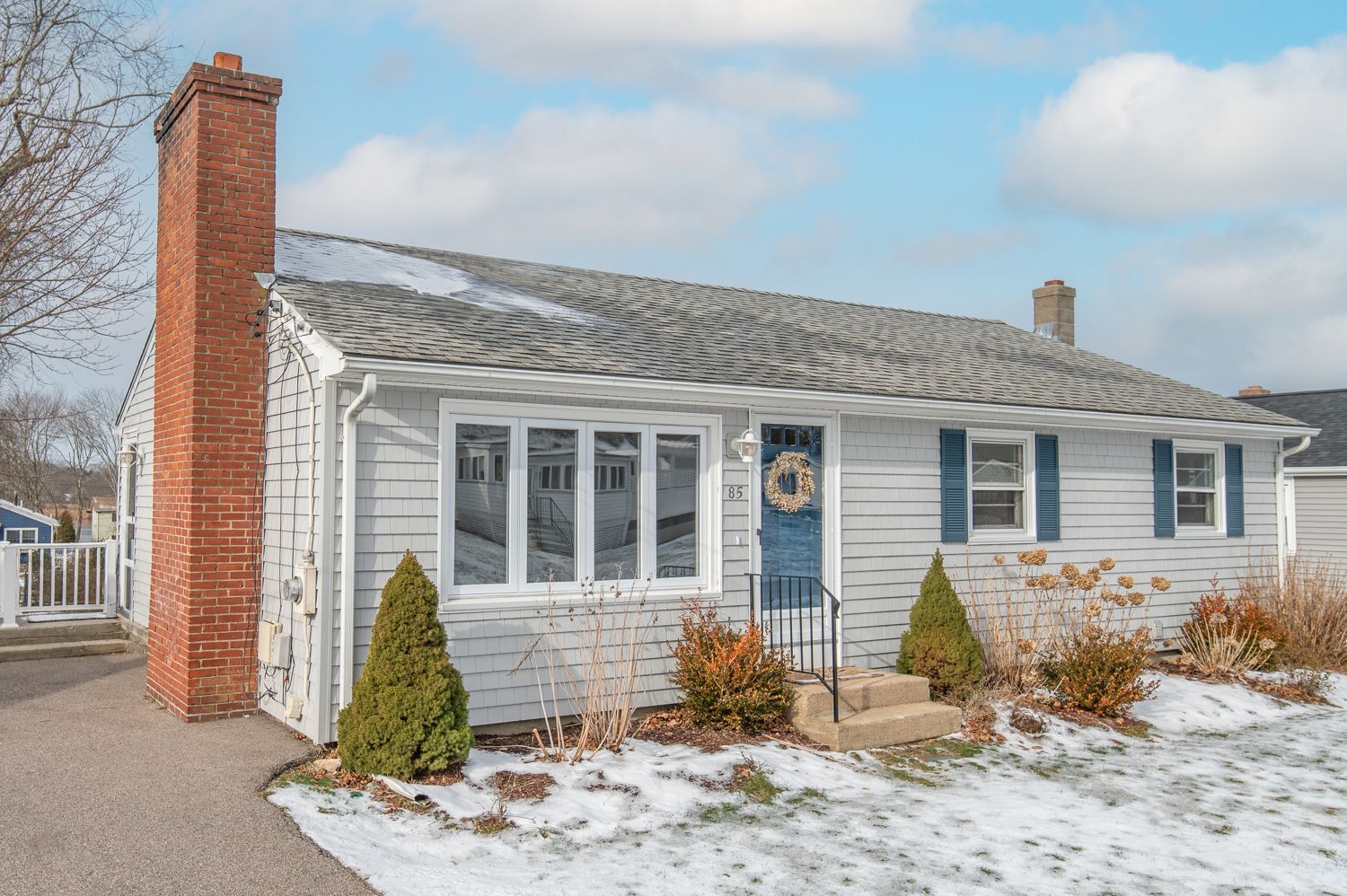 A white house with blue shutters and a brick chimney