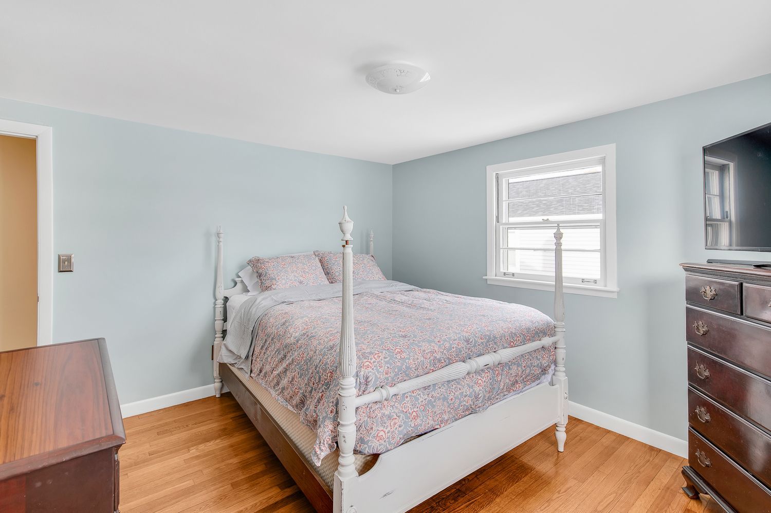 A bedroom with a bed , dresser , and television.