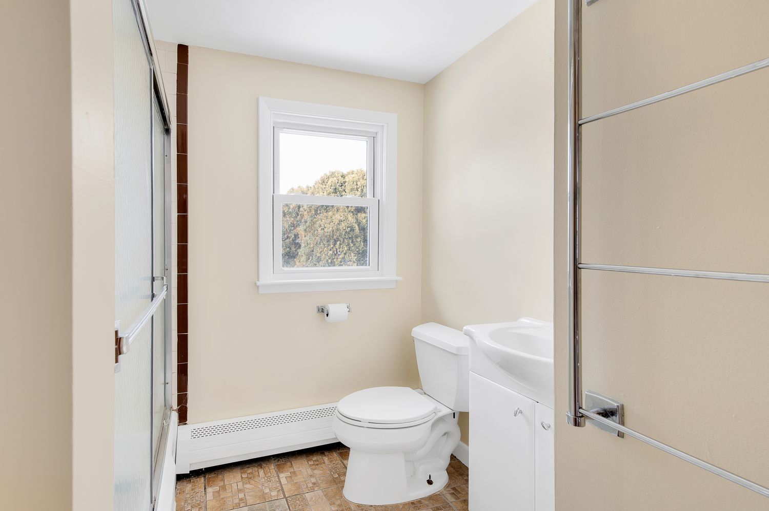 A bathroom with a toilet , sink and window.