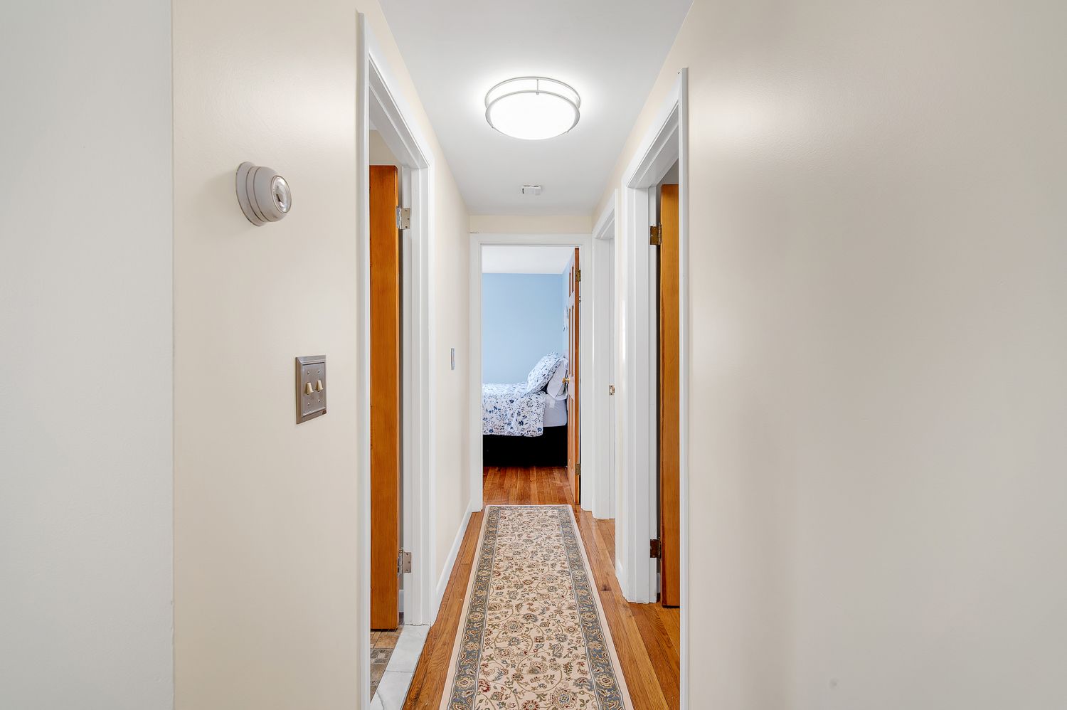 A long hallway with a rug leading to a bedroom.