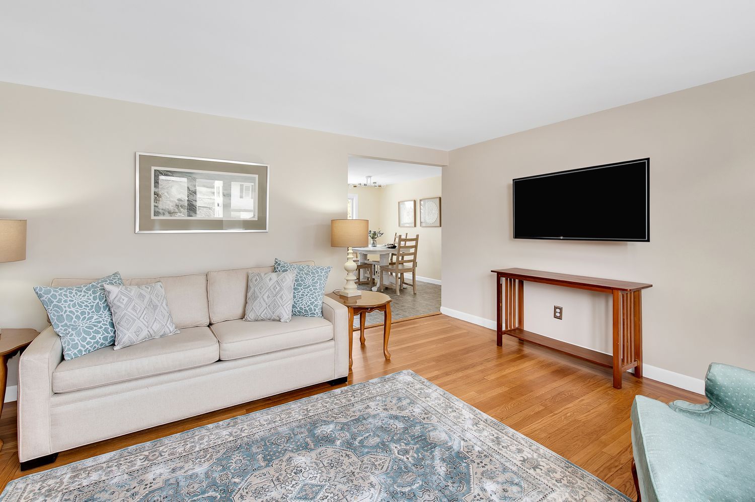 A living room with a couch and a flat screen tv on the wall.