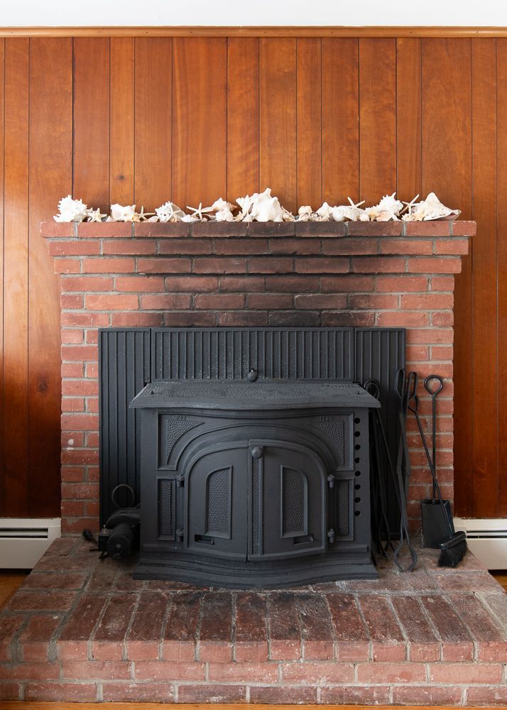 A brick fireplace with a black stove in a living room.