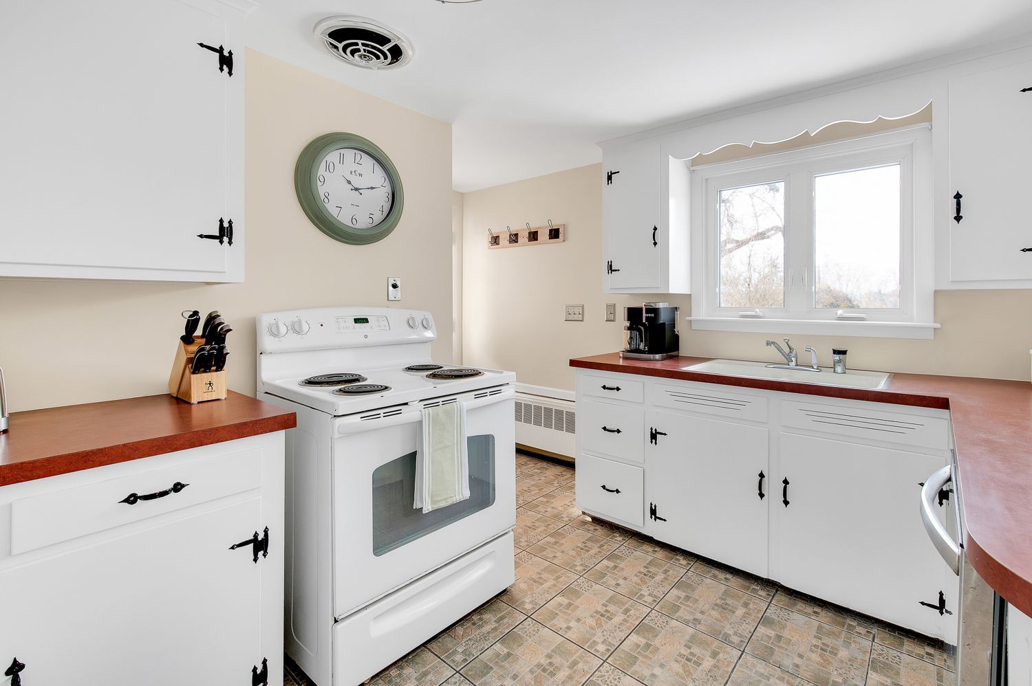 A kitchen with a stove and a clock on the wall