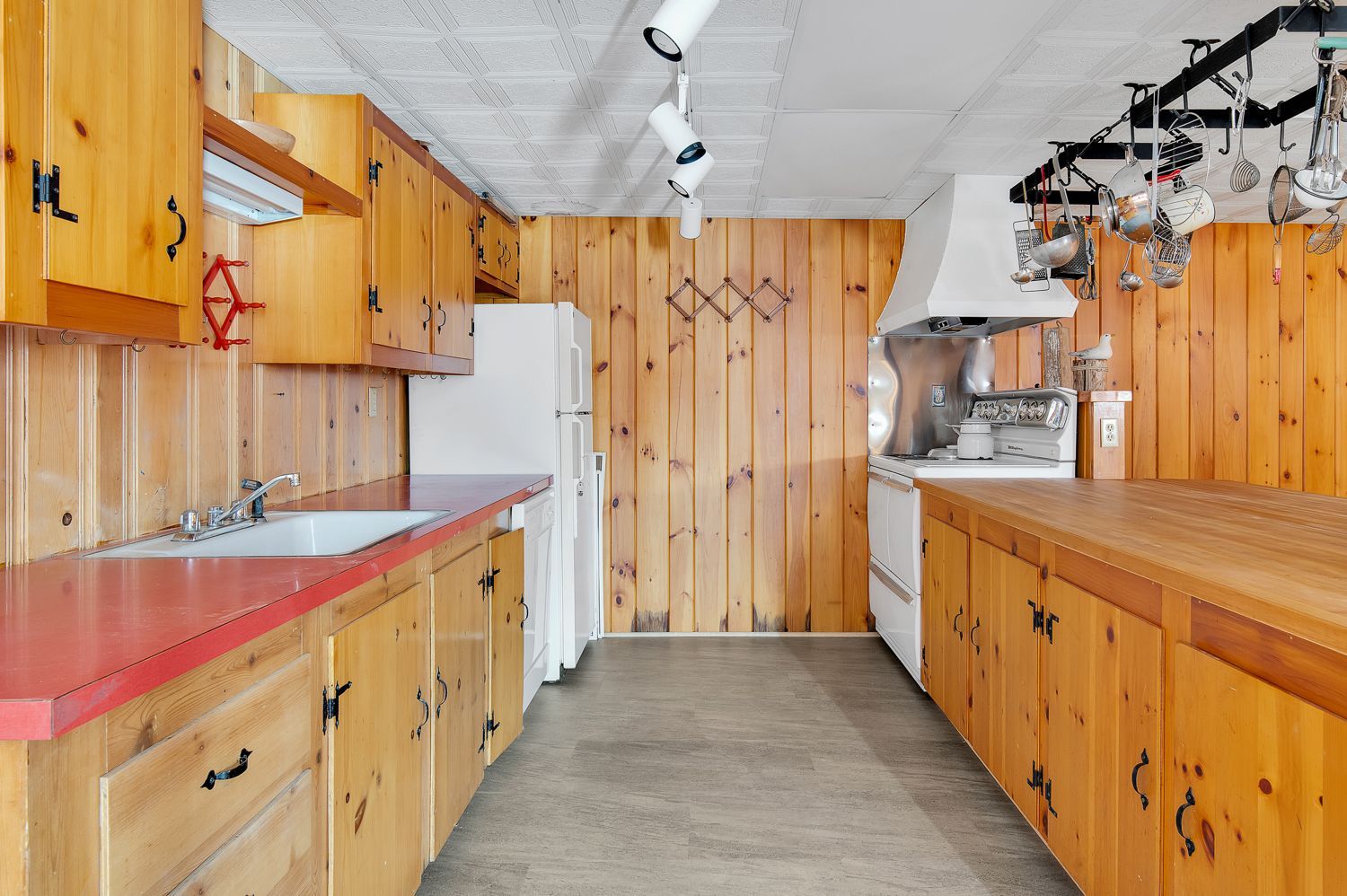 A kitchen with wooden cabinets , a sink , and a refrigerator.