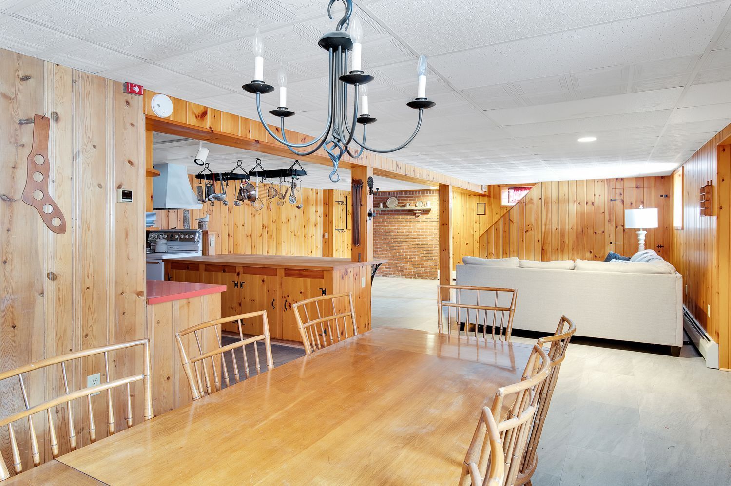 A dining room with a wooden table and chairs and a chandelier hanging from the ceiling.