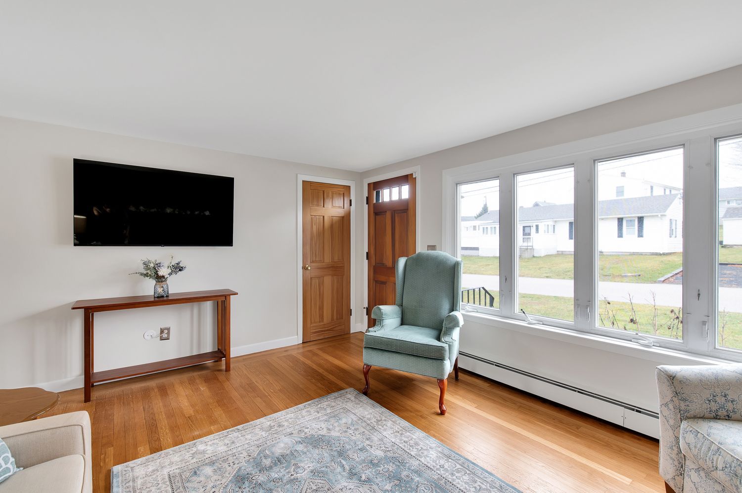 A living room with hardwood floors , a chair and a flat screen tv.