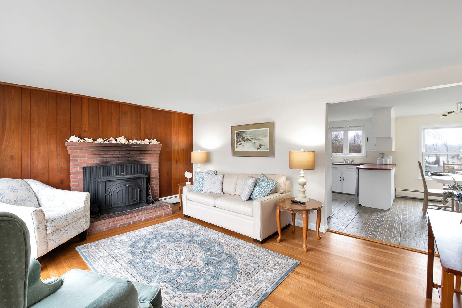 A living room with a couch , chair , fireplace and rug.