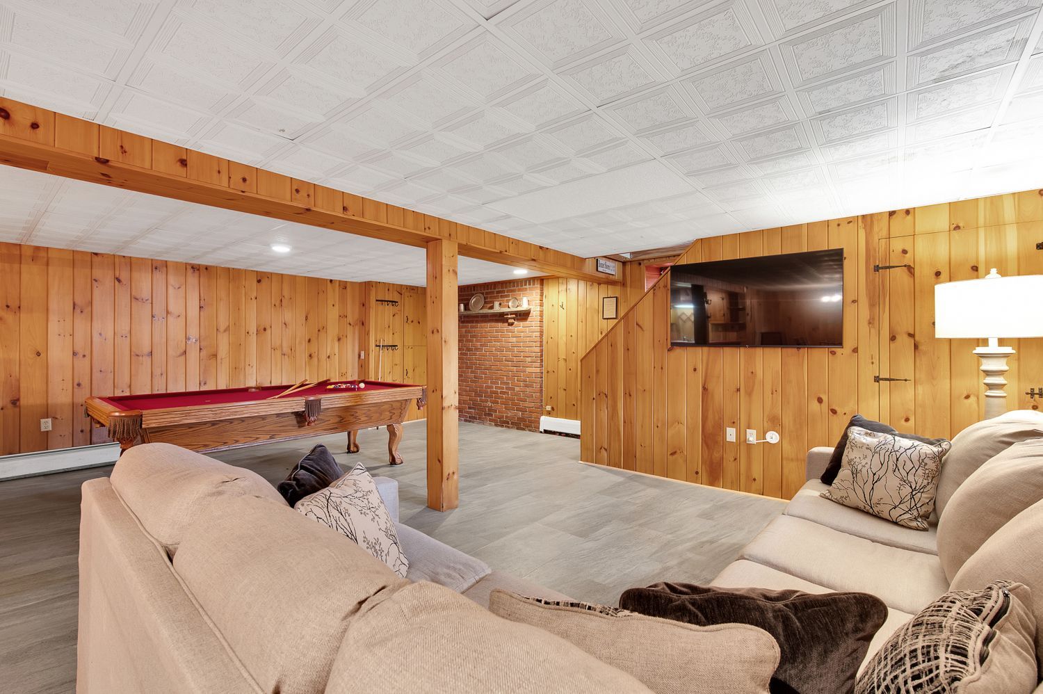 A living room with a pool table and a flat screen tv.