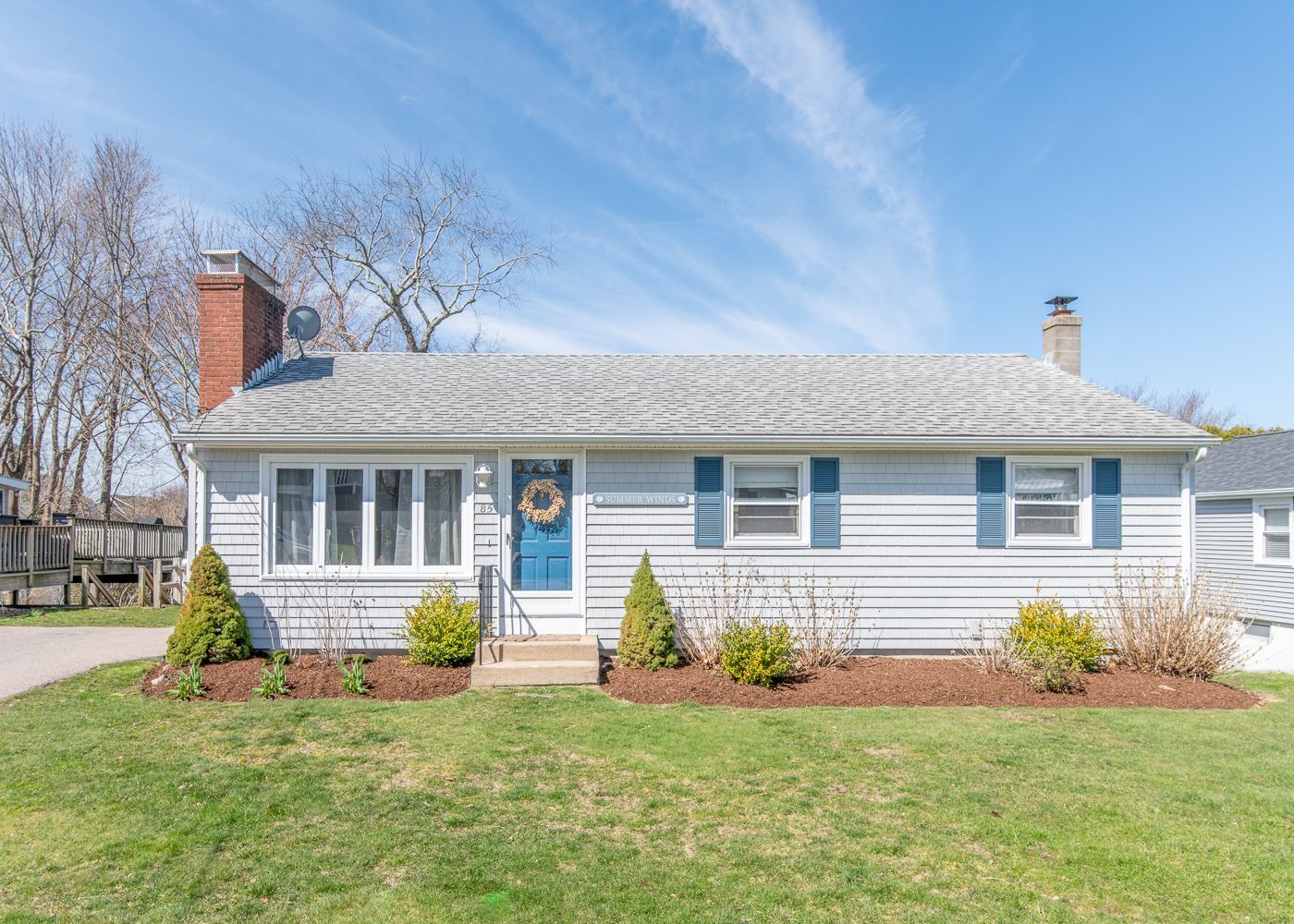 A white house with blue shutters and a blue door is for sale.