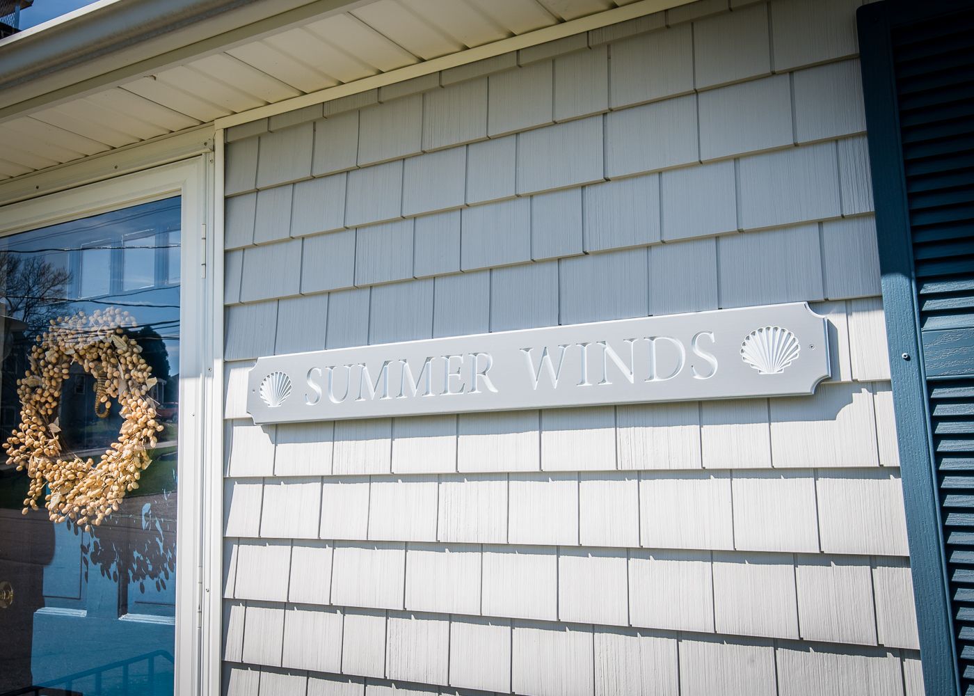A sign on the side of a house says summer winds