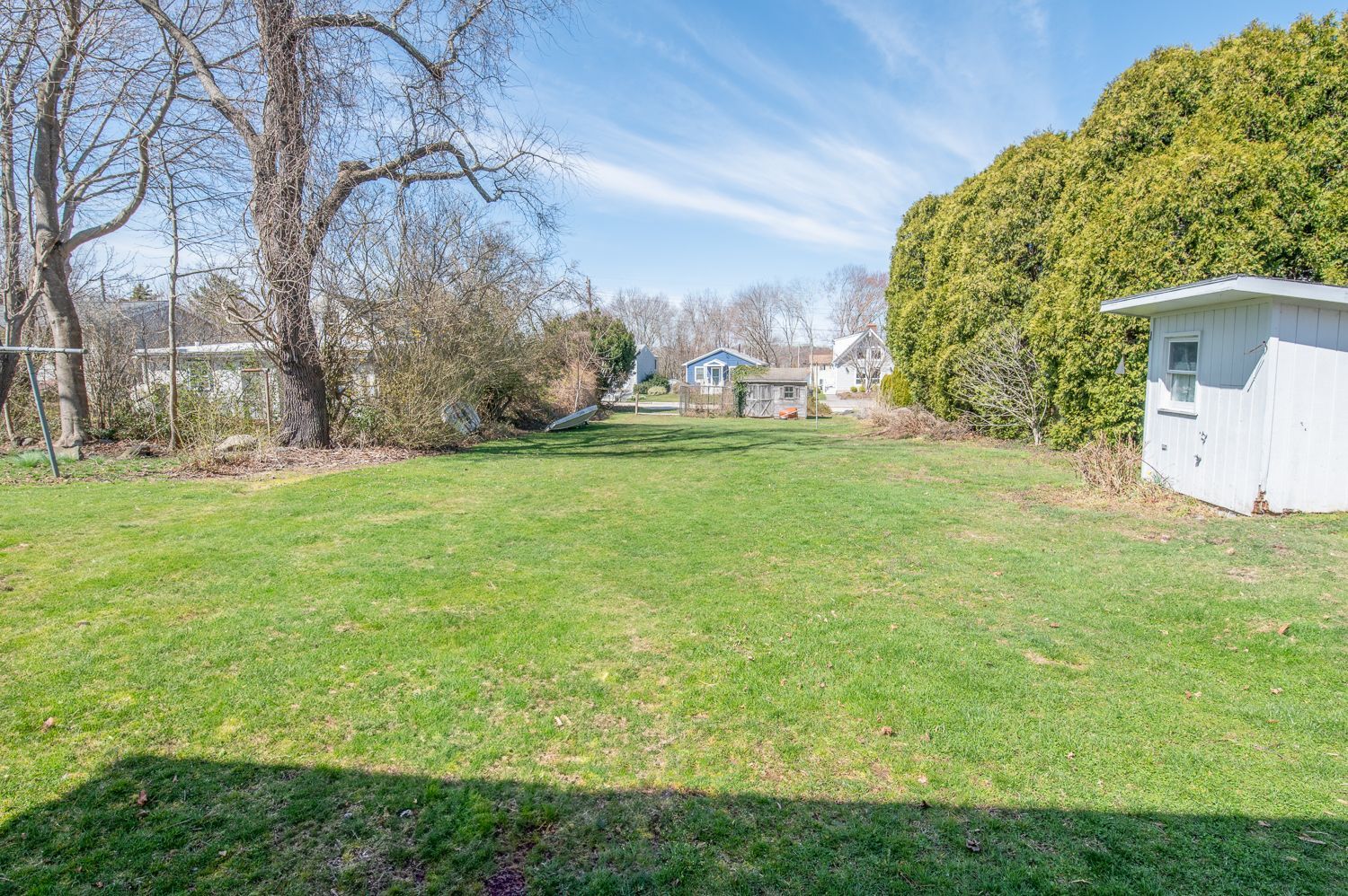 A large lawn with a white shed in the middle of it.