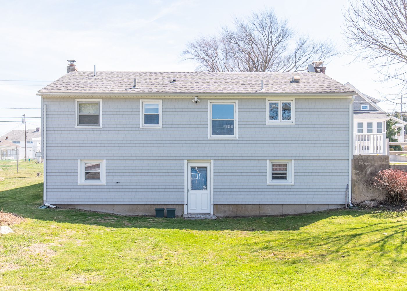 A large house with a lot of windows is sitting on top of a lush green field.
