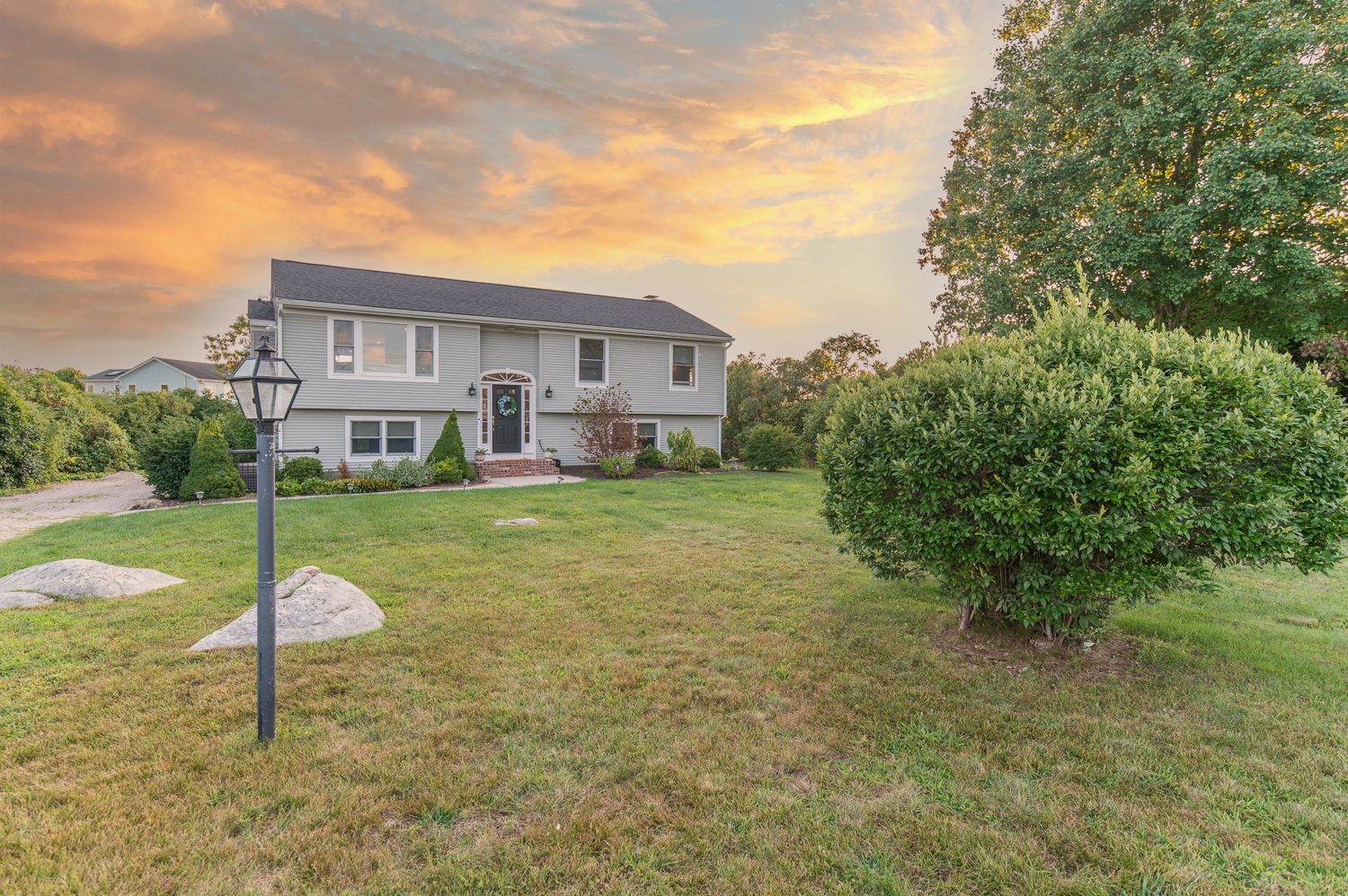 A large house is sitting in the middle of a lush green field.