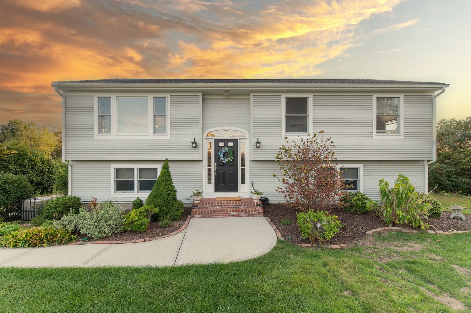 A large white house with a brick walkway leading to the front door.