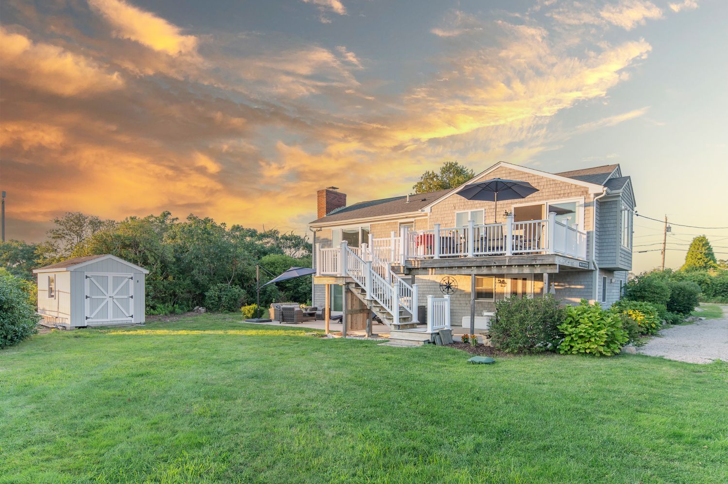 A large house with a large lawn in front of it at sunset.