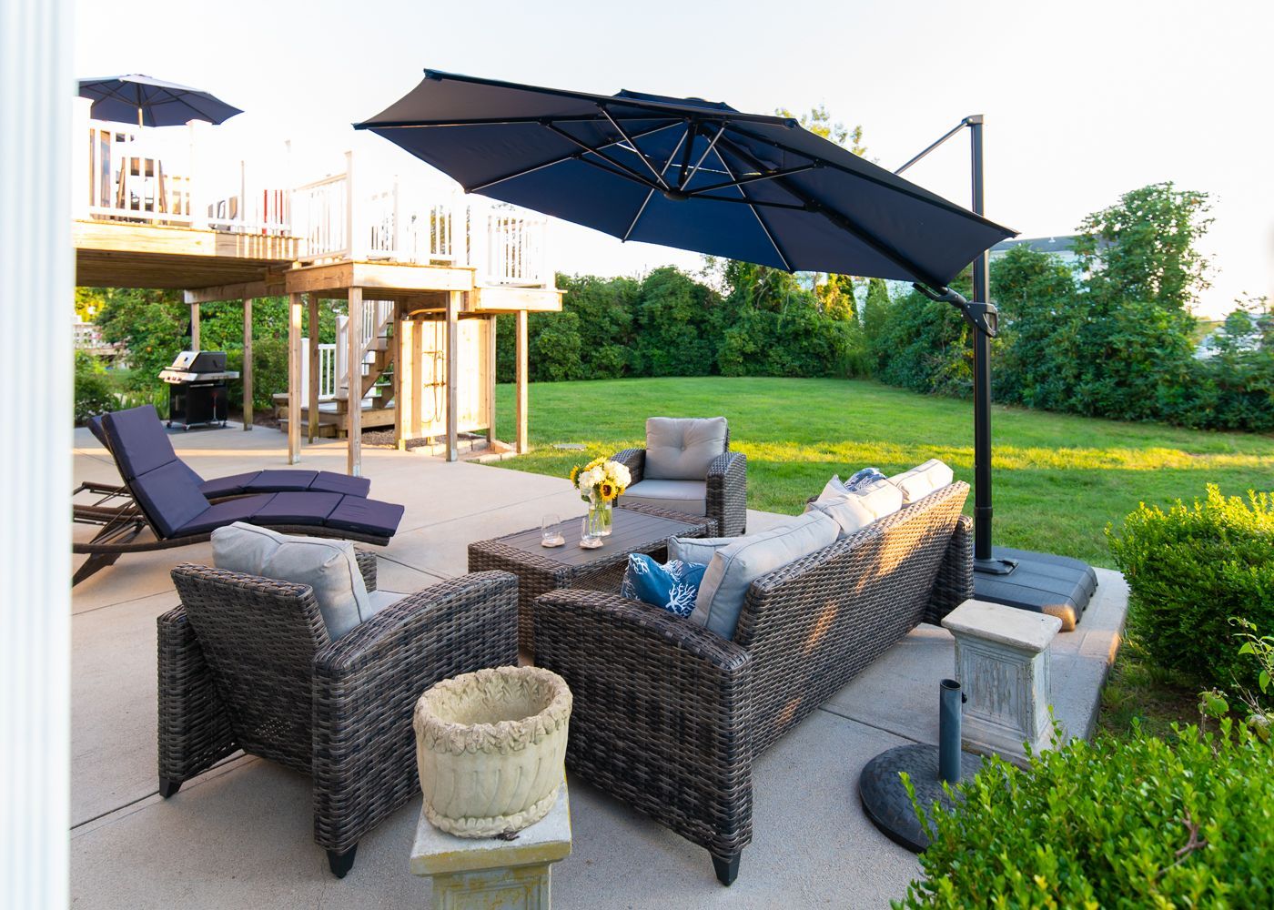A patio with a couch , chairs , table and umbrella.