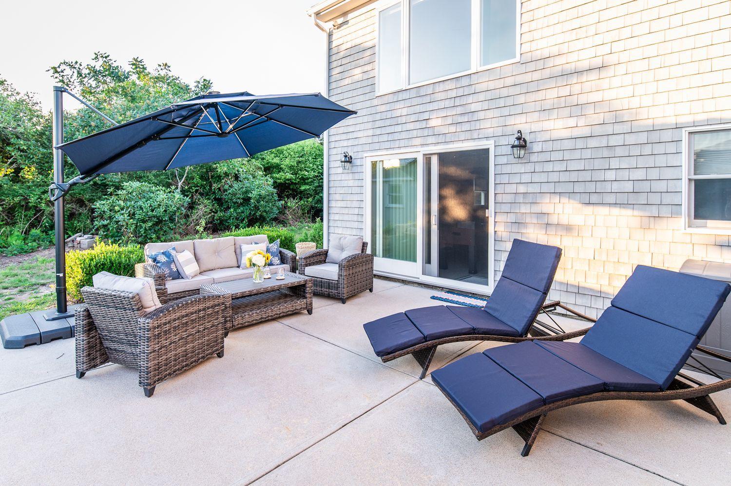 A patio with a couch , chairs , umbrella and lounge chairs.