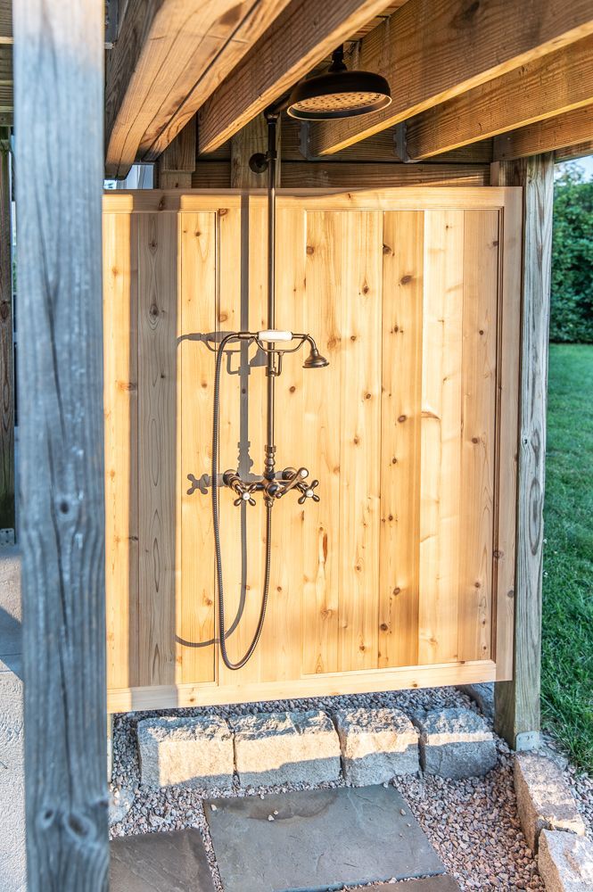 A wooden fence with a shower attached to it.