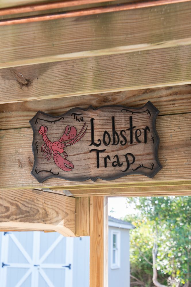 A lobster trap sign is hanging from the ceiling of a wooden structure.