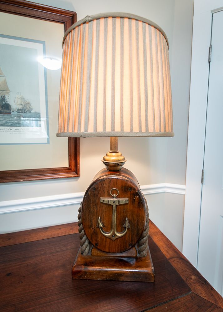 A lamp with an anchor on it is sitting on a wooden table.
