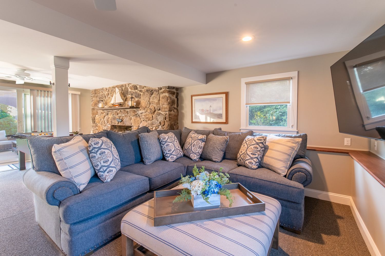 A living room with a blue sectional couch and an ottoman.