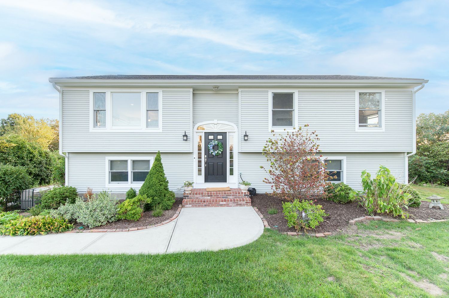 A large white house with a black door and a wreath on the front door.