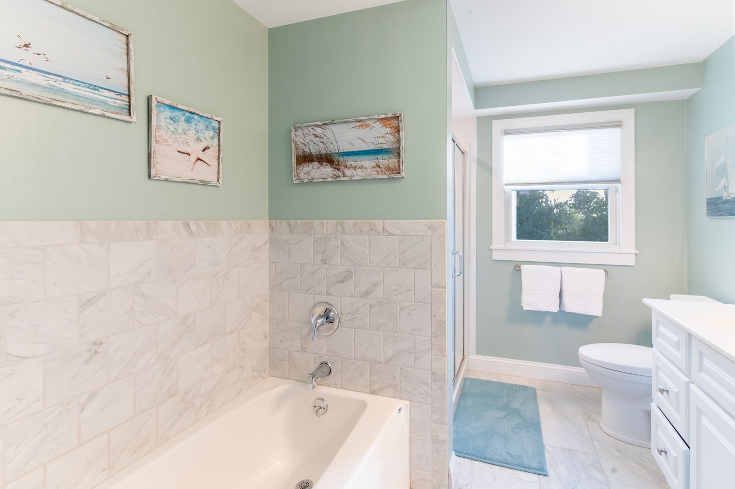 A bathroom with a tub , toilet , sink and window.