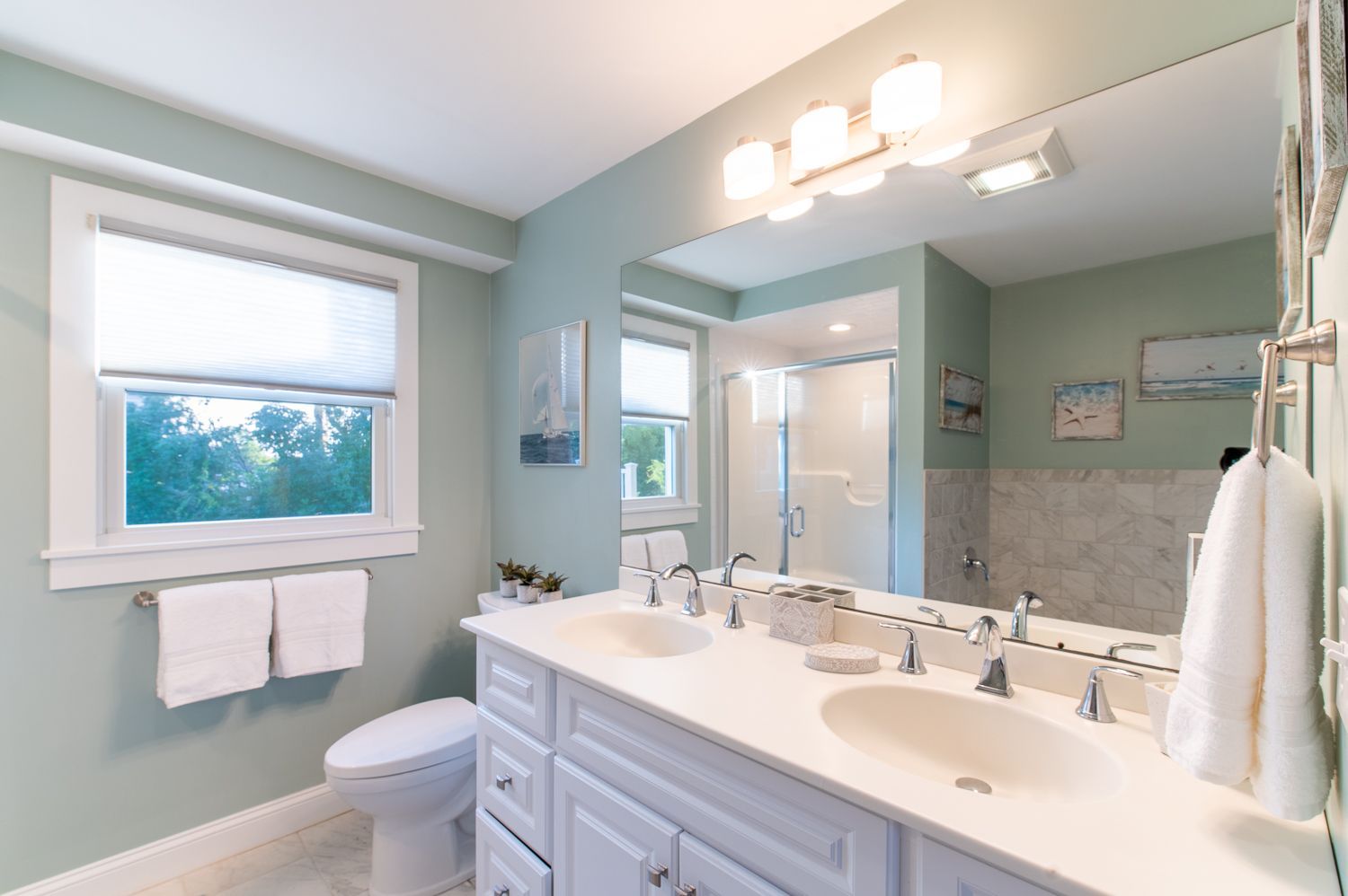 A bathroom with two sinks , a toilet , and a large mirror.