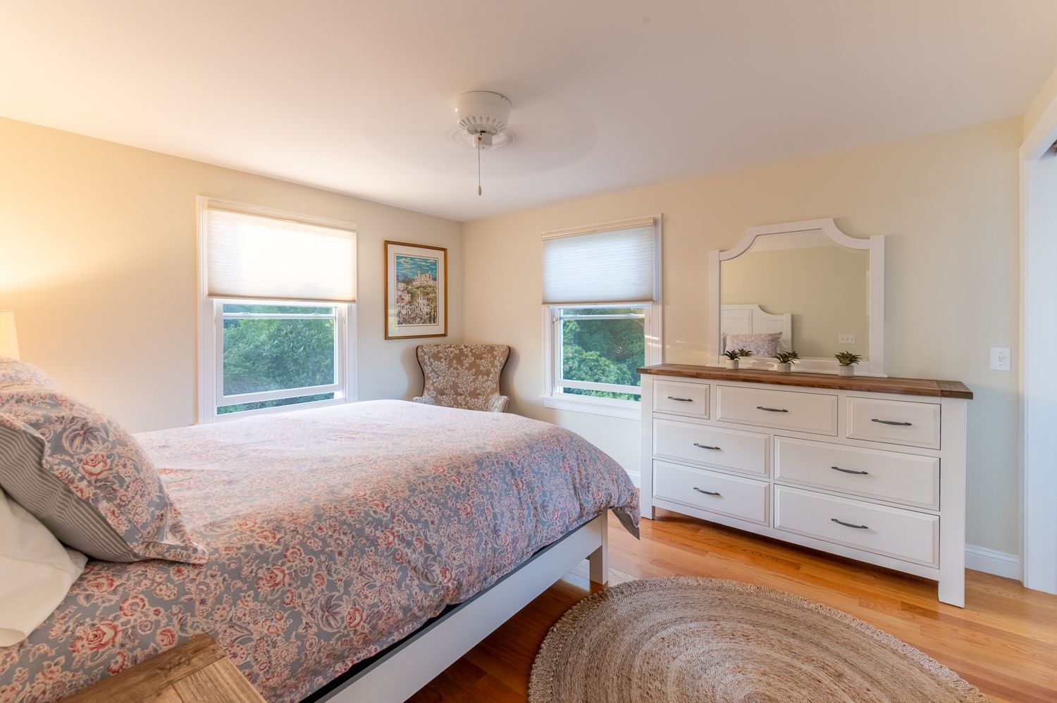 A bedroom with a bed , dresser , and mirror.
