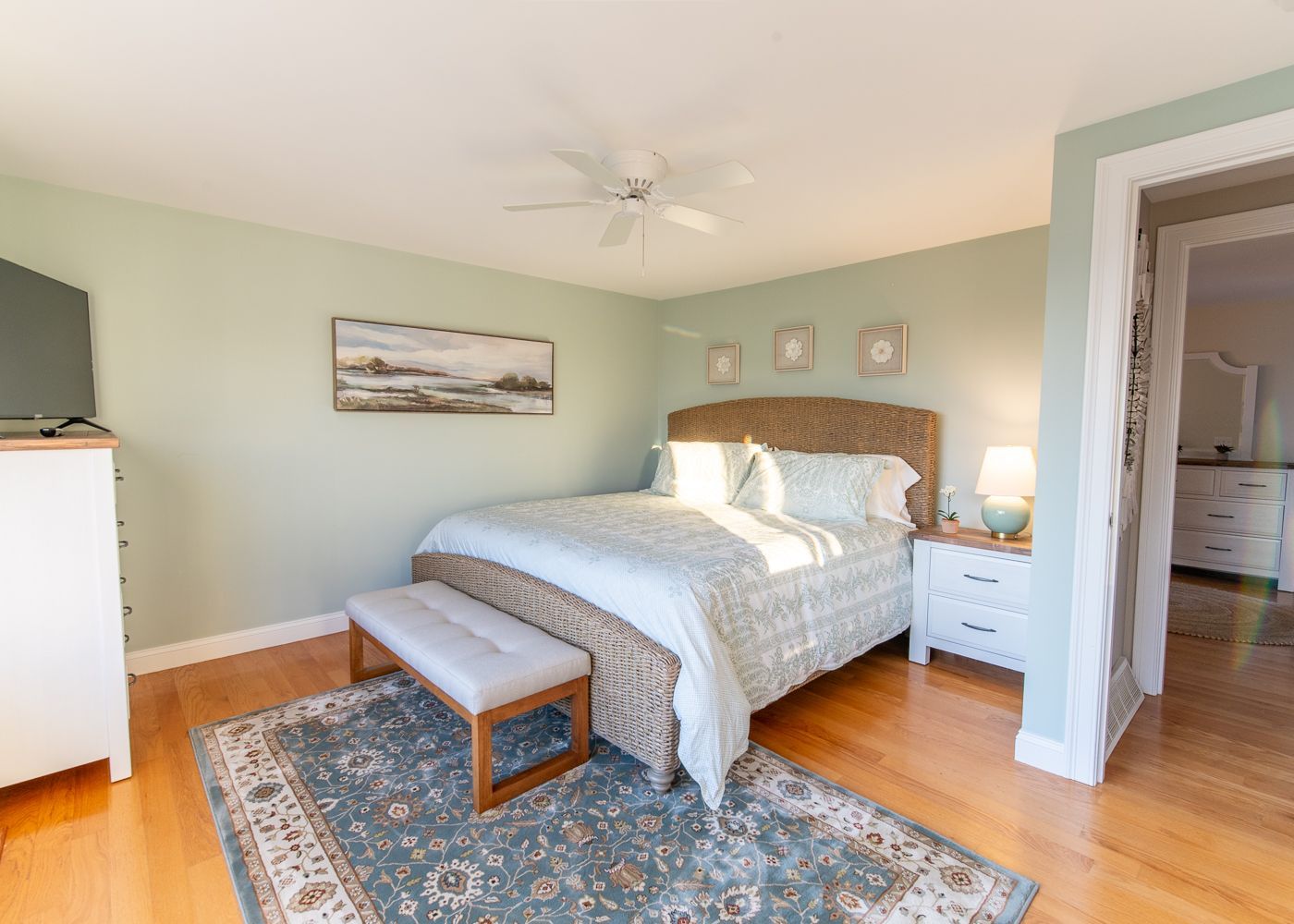 A bedroom with a king size bed , dresser , nightstand , rug and television.