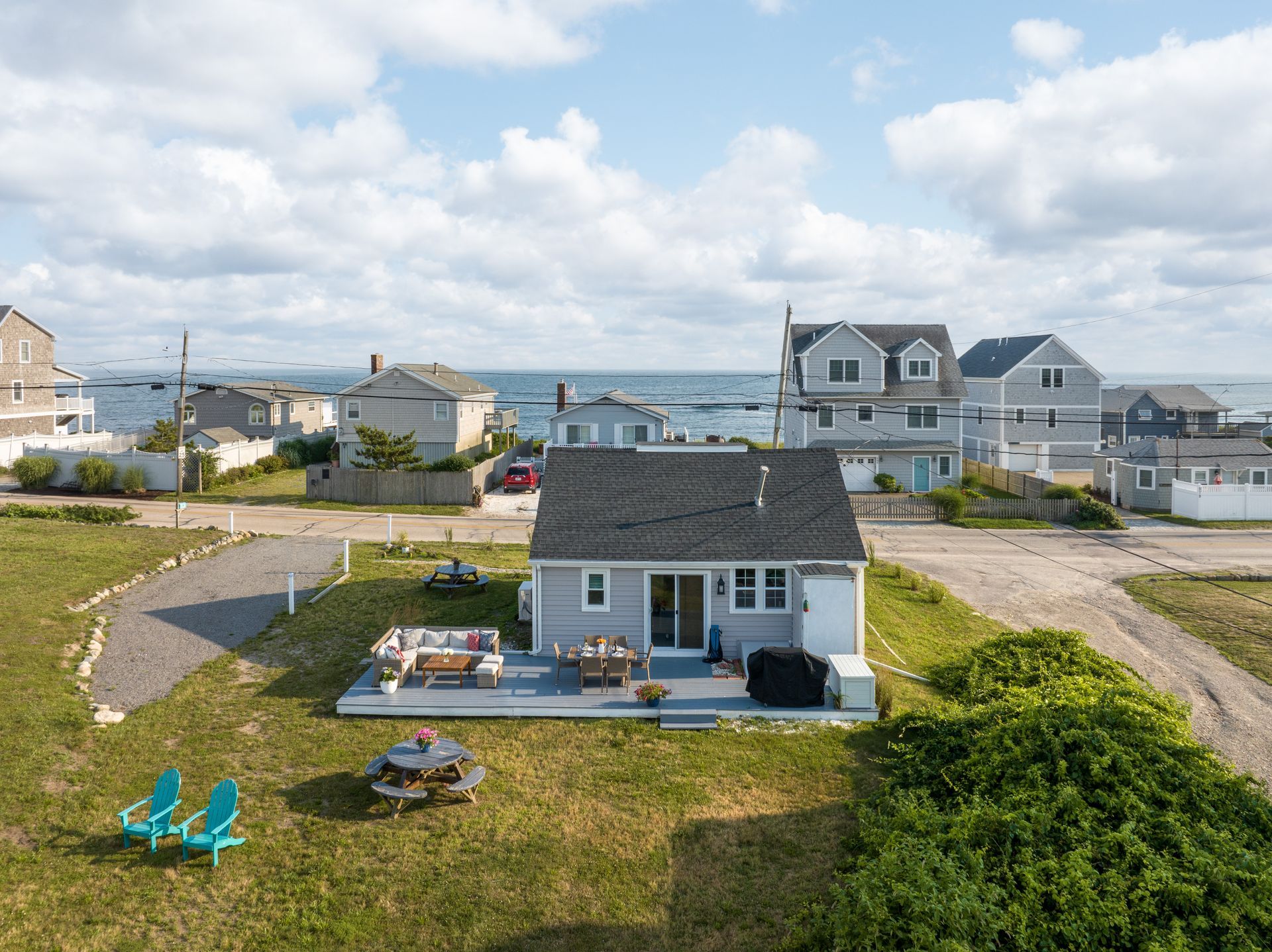 An aerial view of a house with a deck and lawn chairs in front of it.